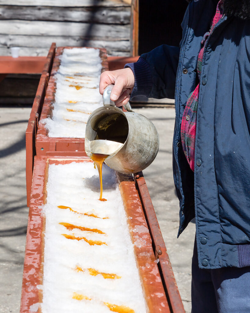 Man pouring hot maple syrup on snow (Adobe Stock)